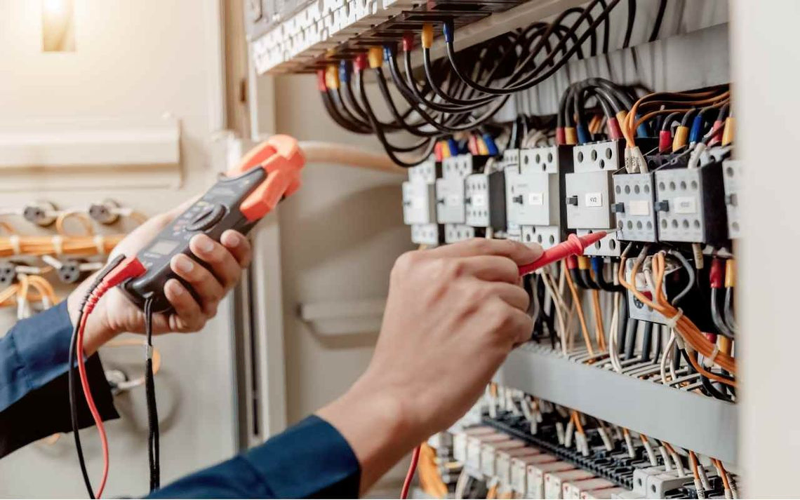 manos de electricista con guantes cortando cables con alicates